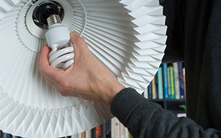 A person changes their energy efficient light bulb, which may use polycarbonate plastic casings.