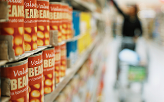 Cans of beans and other vegetables on a grocery store shelf.